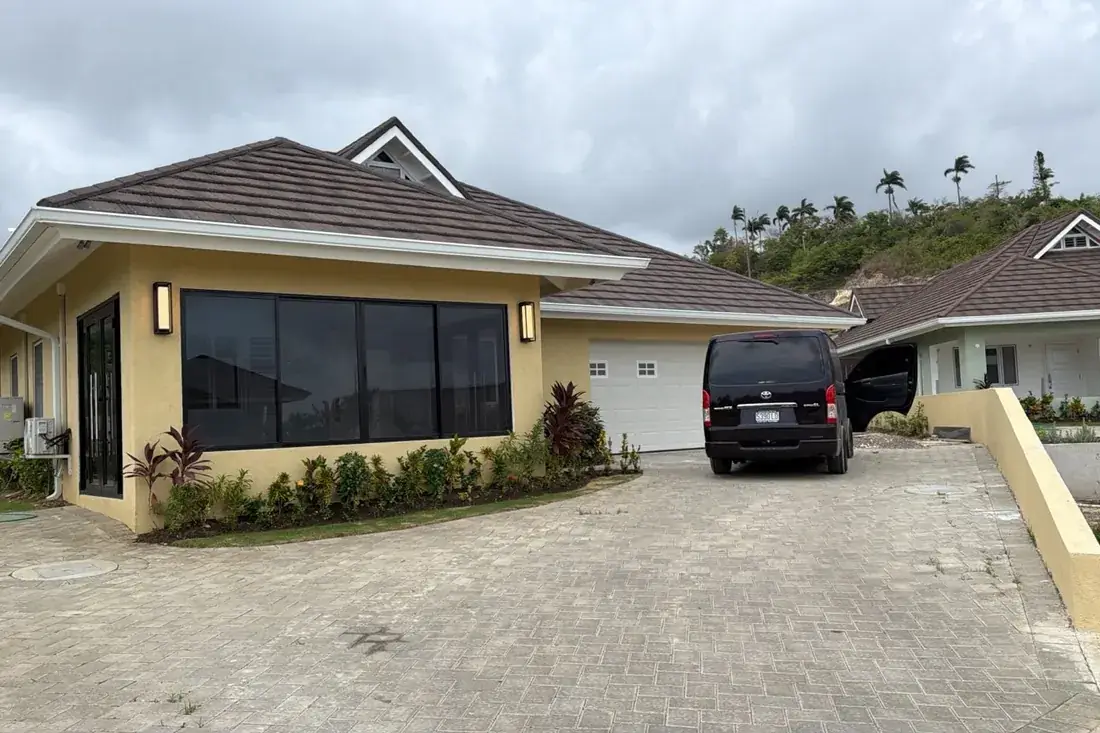 The same house finished, rendered in yellow with the roof on, planting in and the driveway paved