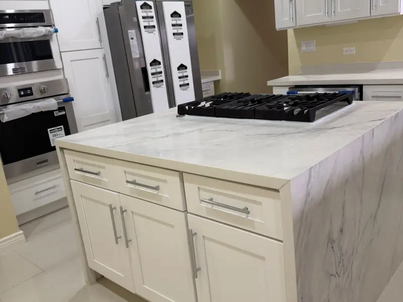 A finished kitchen with a marble island, gas range and stainless extractor
